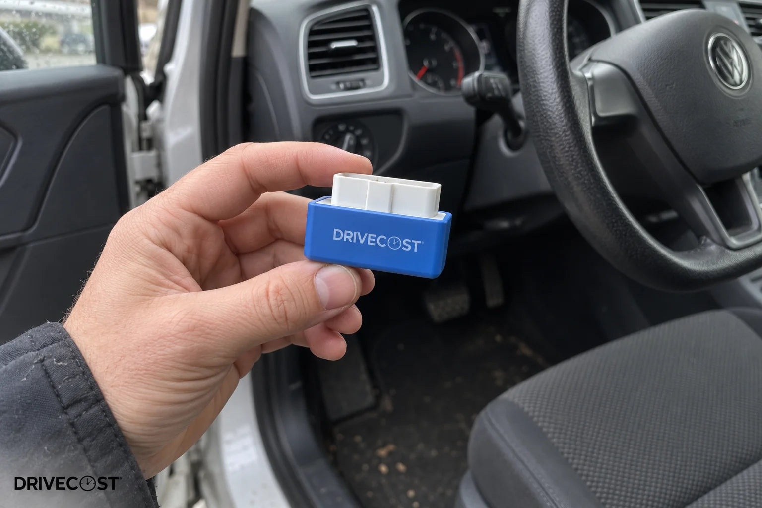 Kompakter DriveCost-Adapter in einer Hand neben dem Fahrzeug, illustrative Anwendungsszene